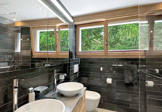 Badezimmer mit Fenster, Dusche, Doppelwaschbecken und Toilette