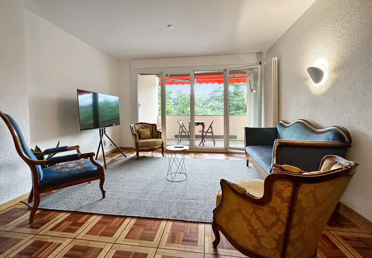 Geräumiges Wohnzimmer mit Fernseher und Blick auf den hellen Balkon, ausgestattet mit Tisch und Stühlen 