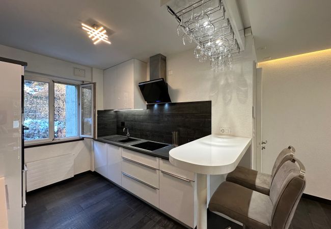 Blick in die Küche mit Fenster und weißer Bartheke mit zwei Hochstühlen