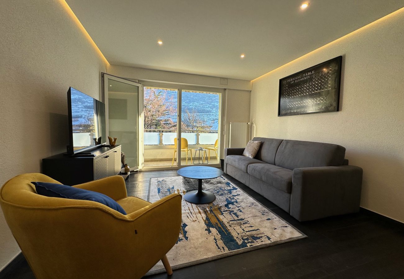 Wohnzimmer mit Sofa und bequemem Sessel, Blick auf den Balkon mit kleinem Tisch und Stühlen, um die Aussicht zu genießen
