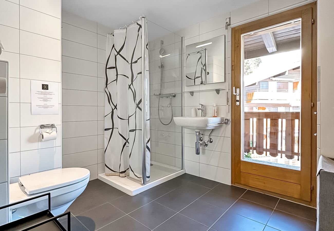Spacious bathroom with shower and toilet, with patio door leading to balcony