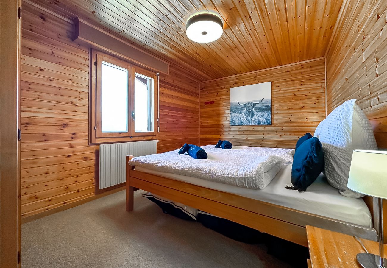A spacious, wood-panelled bedroom with a window and a comfortable Queen Size bed