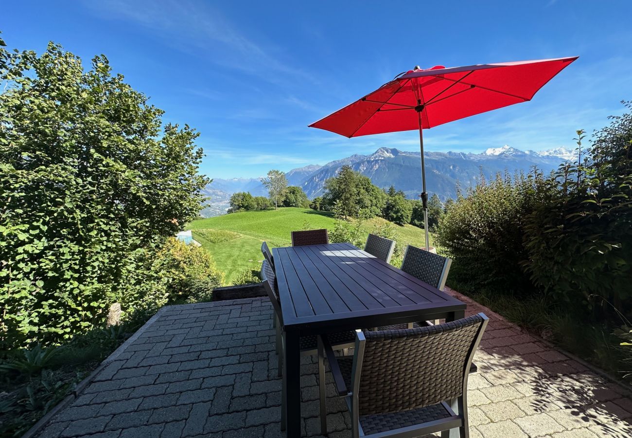 Terrace with tables, chairs and parasol, offering breathtaking views of the Alps