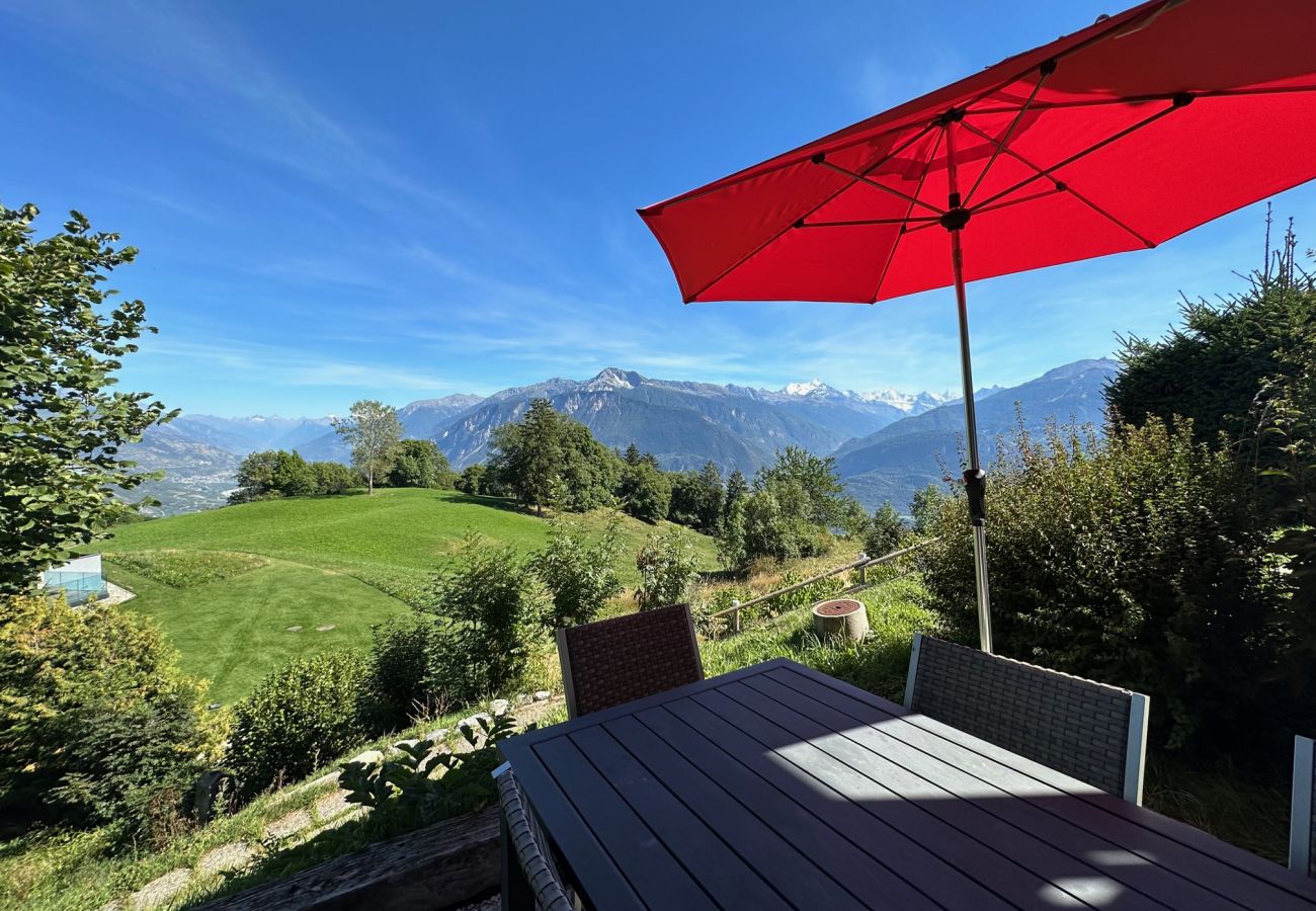 La terrasse du chalet, dotée d'une table et de chaises, offre une vue spectaculaire sur les montagnes.