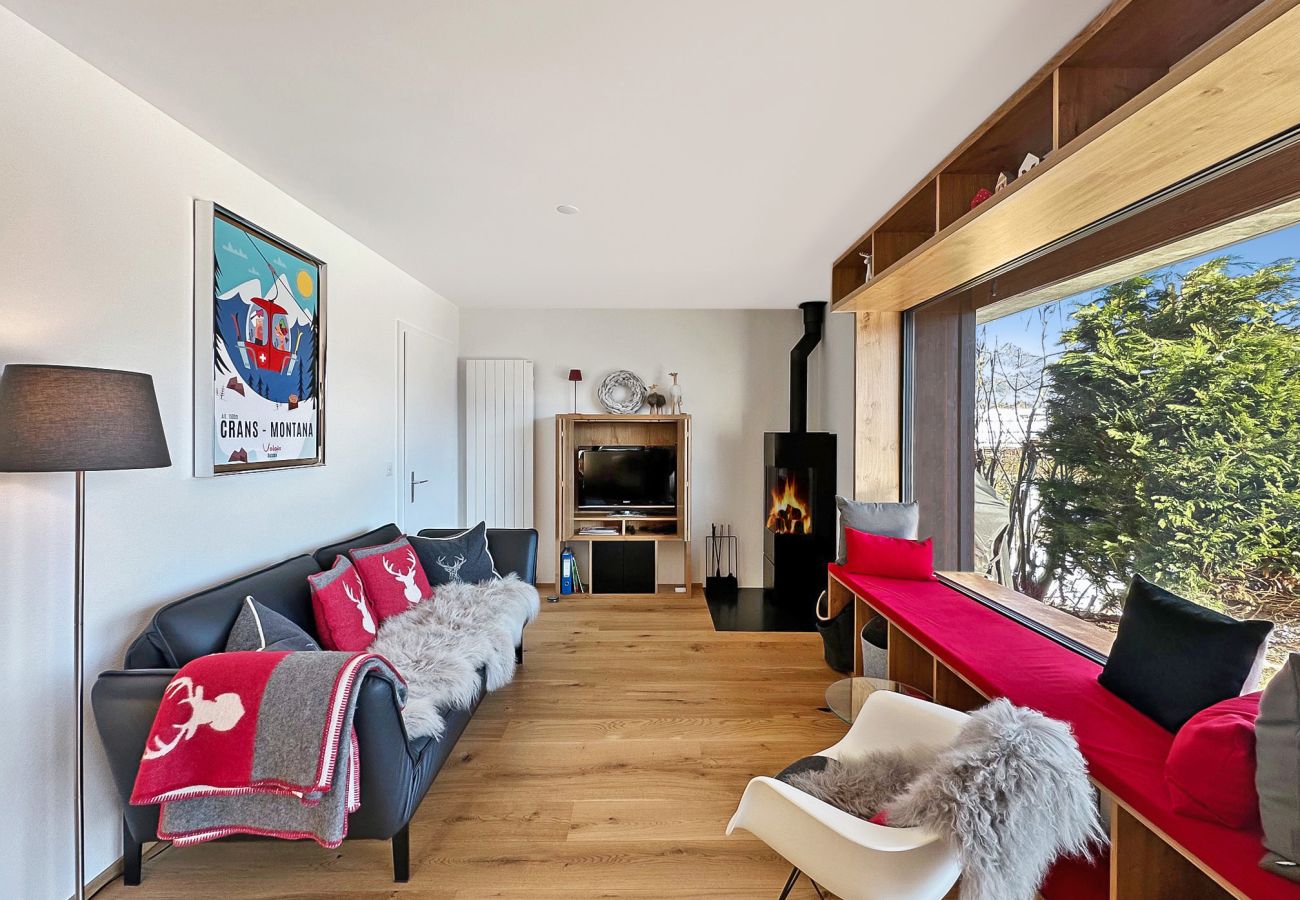 Salon avec cheminée, canapé confortable et fauteuil, offrant une vue exceptionnelle par une grande fenêtre