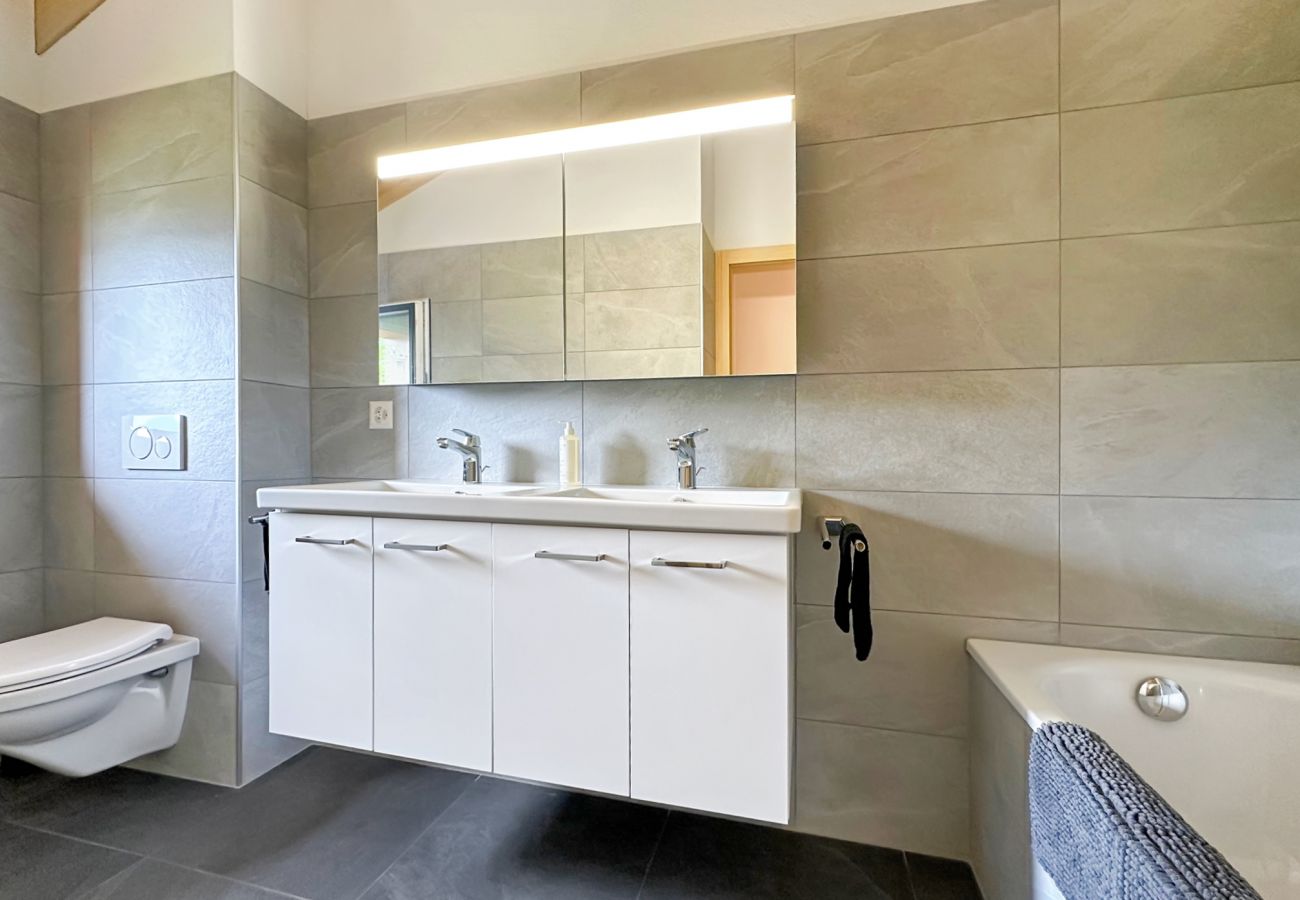Salle de bain flambant neuve équipée d'un WC, de deux lavabos et d'une baignoire