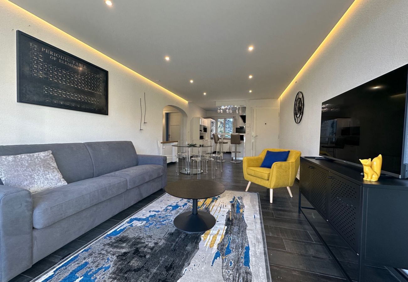 Salon avec télé, en arrière-plan vue sur la salle à manger conviviale et moderne